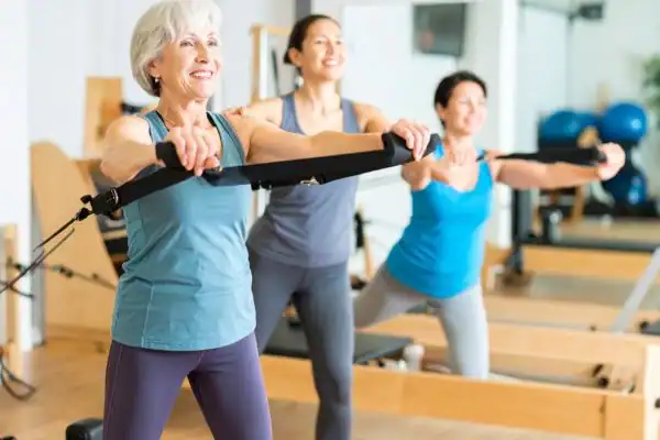 Toning Arms After 60: Empowering Womens Fitness Through Effective Weight Training 2 older woman doing weight training Wilmslow and resistance in the gym to tone upper arms